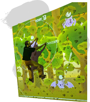 A person climbs an interactive rock wall with a vibrant digital forest scene, including cartoon bats and targets. The score is displayed at 13.